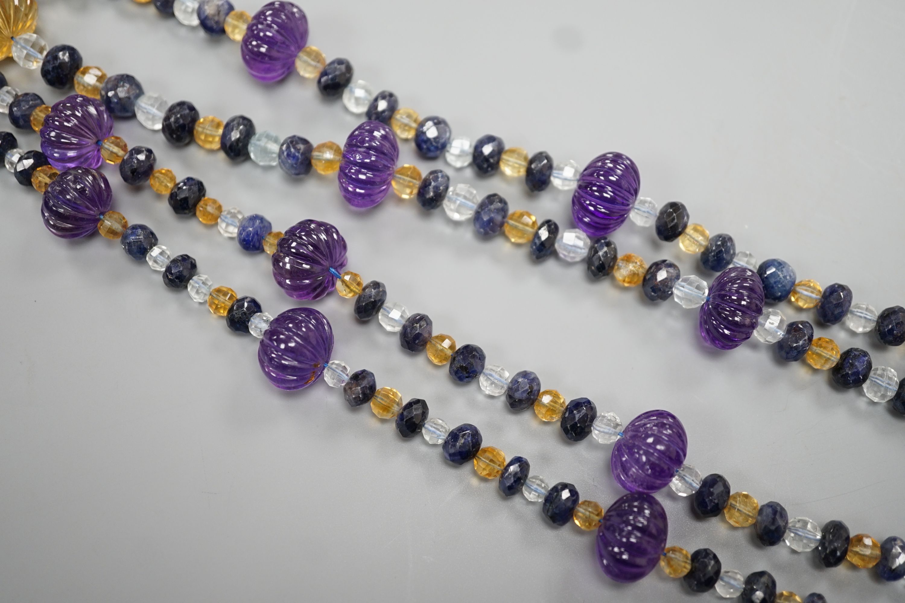 A modern single strand fluted amethyst and facet cut sapphire, citrine and aquamarine bead set necklace, 134cm.